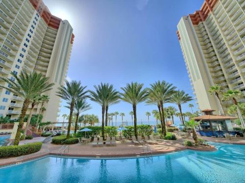 a pool in the middle of two buildings with palm trees at Shores of Panama 1307, Two Masters! Under 25 ok! in Panama City Beach
