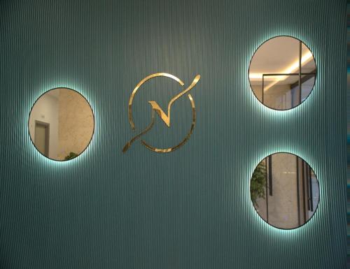 three circular mirrors and a gold symbol on a green wall at Hotel Nimantrana in Noida