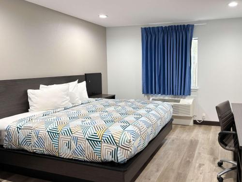 a bedroom with a bed and a blue curtain at Studio 6 Sulphur LA in Sulphur