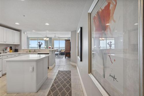 une cuisine avec des placards blancs et une grande peinture murale. dans l'établissement Majestic Condo- Tower 2 #206 3 BR 3 BA Low floor!, à Panama City Beach