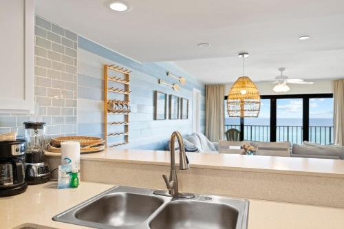 a kitchen with a sink and a living room at Commodore 606 3 BR 3 BA Sleeps 12 in Panama City Beach
