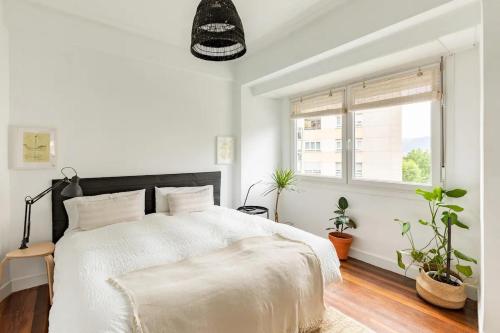 a white bedroom with a bed and a window at 10m Casco Viejo in Bilbao