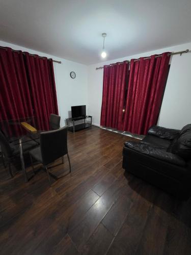 a living room with red curtains and a couch at Glory Home 1 in Dartford