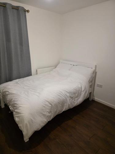 a bed with white sheets and a gray curtain at Glory Home 1 in Dartford