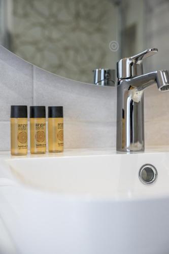 3 bouteilles d'odorisants assises sur un lavabo dans l'établissement Les Orangers, Charmant studio avec coin nuit, incroyable vue sur la ville et la mer, parking, à Menton