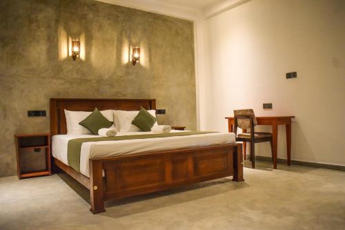a bedroom with a bed and a table and a desk at Nord Mirissa in Mirissa