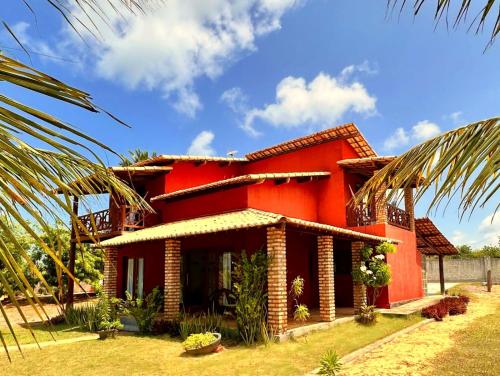 a red house with a palm tree in front of it at Pousada Spa dos Amores in São Miguel do Gostoso