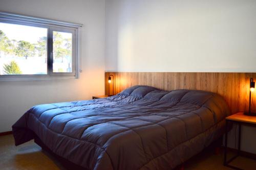 a bed in a bedroom with a window at Villa Maihue departamentos de montaña - Caviahue in Caviahue
