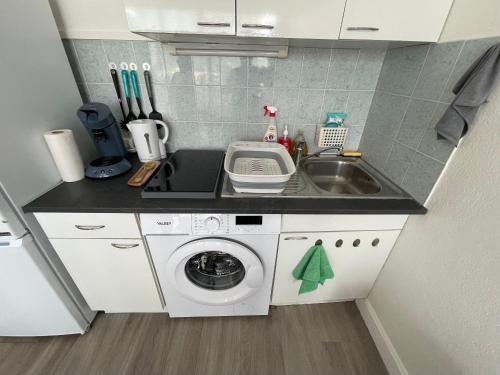 une petite cuisine avec un évier et une machine à laver dans l'établissement Horizon 5 pied dans l'eau, au Lavandou