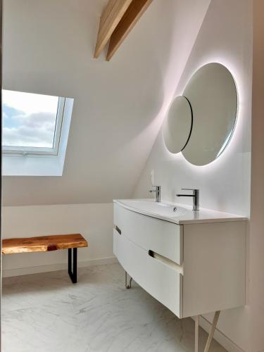 une salle de bain avec un lavabo et un miroir au mur dans l'établissement Grande maison avec jacuzzi couvert, à Riec-sur-Bélon