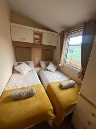 two beds in a small room with a window at Skiddaw Lodges- The Lake District in Plumbland