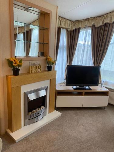a living room with a fireplace and a television at Skiddaw Lodges- The Lake District in Plumbland