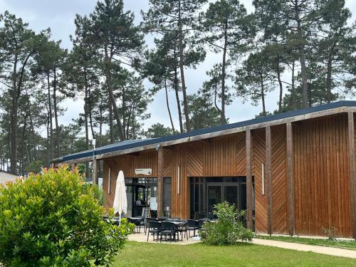 a wooden building with tables and chairs in a yard at MH 475 ELEGANZIA 2CH ET 1sdb dans camping 4 étoiles avec parc aquatique in Saint-Julien-en-Born