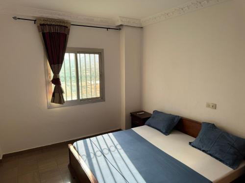 a bedroom with a bed with blue pillows and a window at Le coin paisible - Yaoundé, Omnisports in Yaoundé