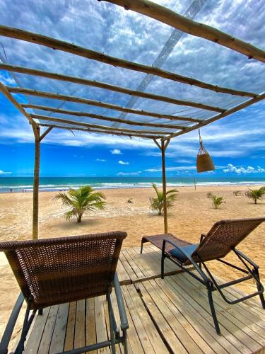a deck with a table and chairs on the beach at Pousada Pé na areia in Camaçari