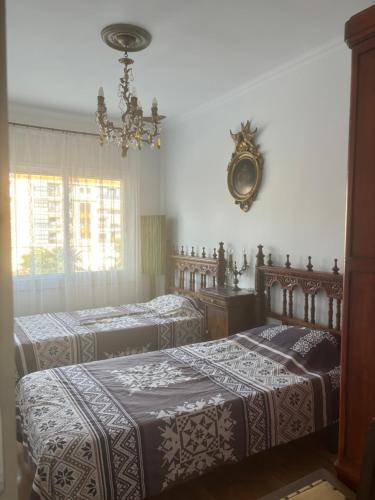 a bedroom with two beds and a chandelier at Luxury Apartamenty in Pineda de Mar