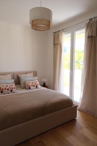 une chambre avec un grand lit et une grande fenêtre dans l'établissement Magnifique T3 de 85m2 de standing vue mer trottel, à Ajaccio