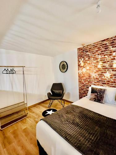 - une chambre avec un mur en briques, un lit et une chaise dans l'établissement Le loft 62 mdh Calais côte d opale plage, à Calais