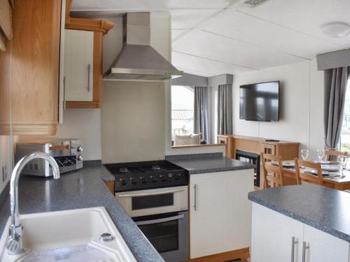 a kitchen with a stove and a sink at Skiddaw Lodges- The Lake District in Plumbland
