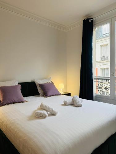 - un grand lit blanc avec 2 serviettes dans l'établissement Luxueux 2 pièces au cœur du 16e, à Paris