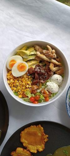 a bowl of food with eggs and vegetables on a table at Eco Hostel y Cabañas Duck House in La Vega