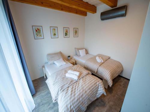 two beds in a room with white walls and wood ceilings at Apartment near Pern tejn Castle in Smr ek in Ujčov