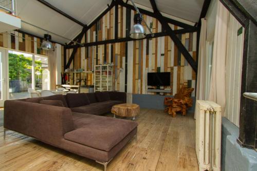 a living room with a brown couch and a table at Paardenstal, Private House with wifi and free parking for 1 car in Weesp