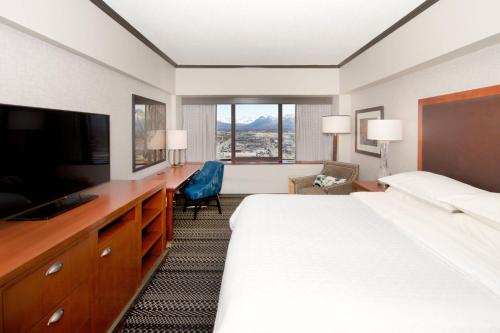 a hotel room with a bed and a flat screen tv at Sheraton Anchorage Hotel in Anchorage