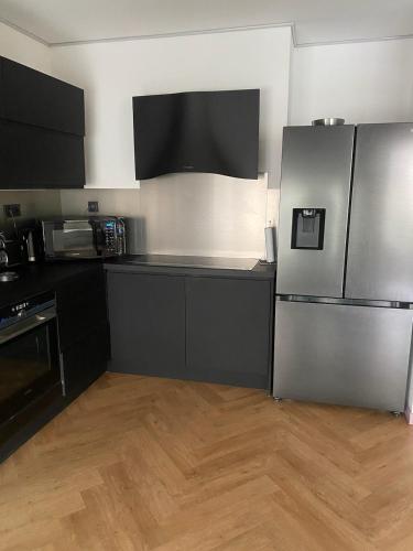 une cuisine avec des appareils électroménagers en acier inoxydable et des armoires noires dans l'établissement Appartement Trocadéro, à Paris