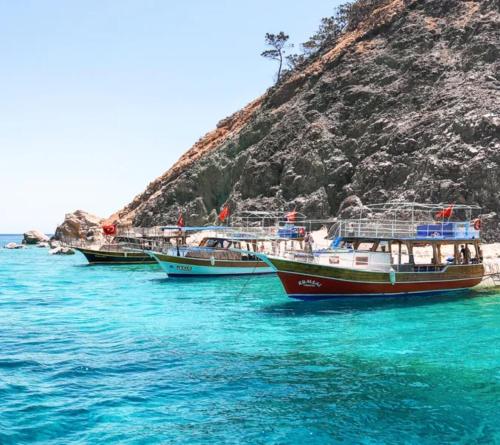 three boats sitting in the water next to a hill at Cozy Mountain View House Near Olympos & Adrasan in Kumluca