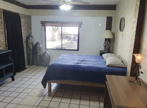a bedroom with a blue bed and a window at Torreón - Casa cerca del aeropuerto con alberca priv in Torreón