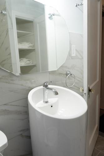 a white bathroom with a sink and a mirror at Sunnyside Nest in Washington, D.C.