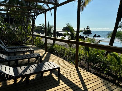 two benches on a deck looking out at the beach at Jenené Lodge Nuquí in Nuquí