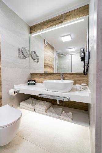 a bathroom with a sink and a toilet and a mirror at LemonApartments in Bucharest