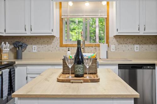 a bottle of wine and two glasses on a kitchen counter at Mountain Oasis Hot Tub Game Room Fire Pit in Pocono Summit