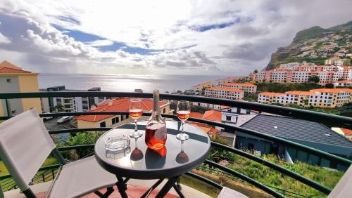 a table with two glasses of wine on a balcony at Perfume a Maresia in Câmara de Lobos