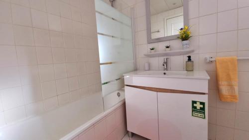 a white bathroom with a sink and a bath tub at Perfume a Maresia in Câmara de Lobos