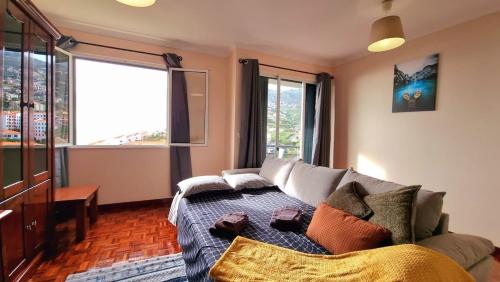 a living room with a couch and some windows at Perfume a Maresia in Câmara de Lobos