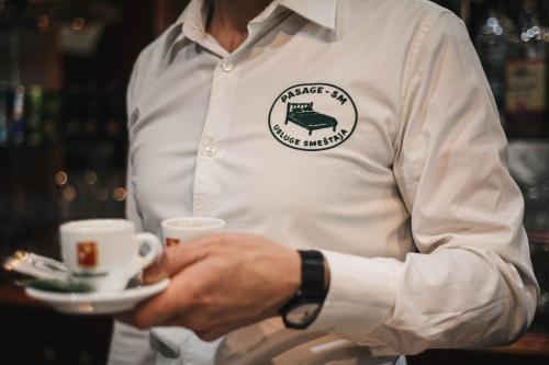 a man holding a plate with a cup of coffee at B&B Passage in Sremska Mitrovica