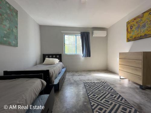 a bedroom with two beds and a dresser and a window at Villa Santorini - Quinta con alberca en el barrial Santiago NL in Santiago