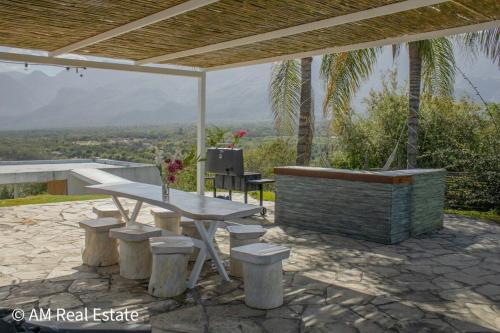 a patio with a table and stools and a view at Villa Santorini - Quinta con alberca en el barrial Santiago NL in Santiago