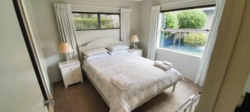 a small bedroom with a bed and two windows at Aquila Haven in Whitianga