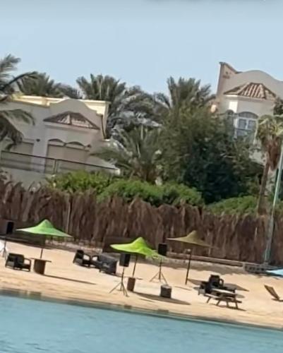 a pool with tables and umbrellas next to a house at درة العروس - شاطيء الحالمة - شاطيء صالح للسباحة - شاليه فاخر in Durat  Alarous