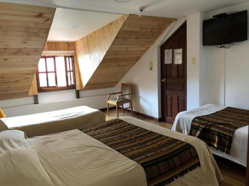 a hotel room with two beds and a flat screen tv at Casa del Arupo in Quito