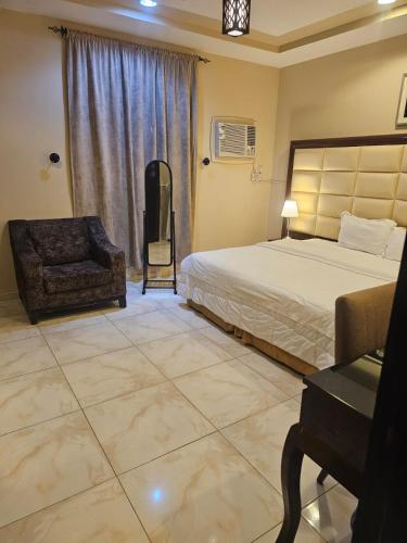 a bedroom with a bed and a chair and a desk at رؤى القنفذة للشقق المخدومة in Al Qunfudhah