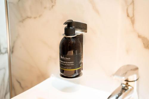 a bottle of soap sitting on a bathroom sink at High Street Hideaway in Fort William