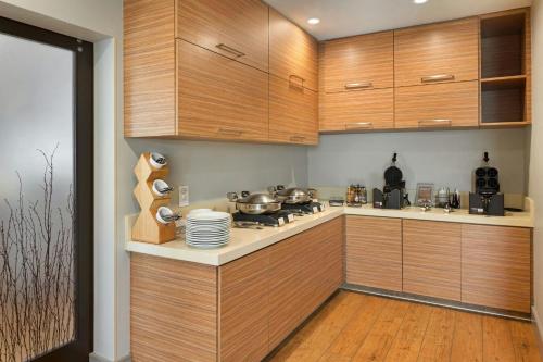 una cocina con armarios de madera y una barra con ollas y sartenes en TownePlace Suites by Marriott Ontario Airport, en Rancho Cucamonga