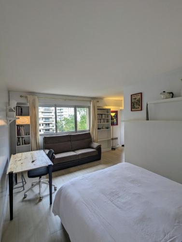 - une chambre blanche avec un lit et un canapé dans l'établissement Studio cosy, refait à neuf, à Paris
