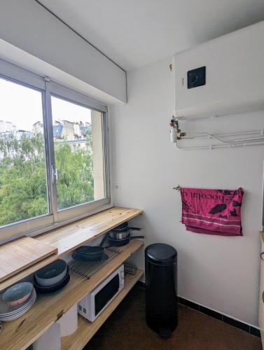 Cette chambre dispose d'une fenêtre et d'une étagère avec de la vaisselle. dans l'établissement Studio cosy, refait à neuf, à Paris