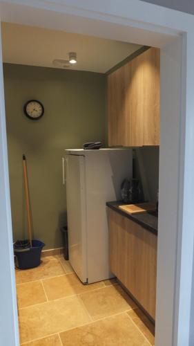 Il comprend une cuisine équipée d'un réfrigérateur et d'une horloge murale. dans l'établissement APP Le Goury, à Valognes